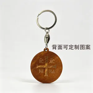 Close-up of a carved cross and IC XC NI KA lettering on a round wooden keychain with metal ring