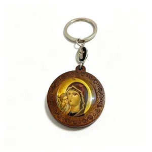Wooden keychain detail with a glass-covered icon, carved border and small cross charm