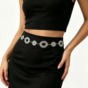 Model draagt een zilveren tailleketting met opengewerkte ringen op een zwarte rok