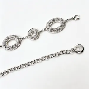 Detail van zilverkleurige opengewerkte ovale schakels, karabijnhaak en verlengketting
