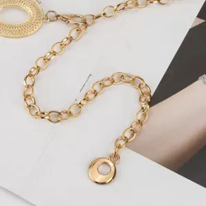 Close-up van een goudkleurige ovale schakelketting met ronde hanger en karabijnsluiting