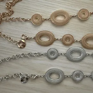 Close-up van goud- en zilverkleurige kettingen met opengewerkte ovale en ronde schakels op hout