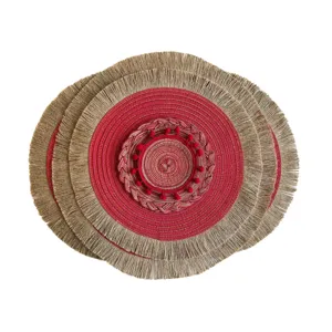 Round woven placemat set in red and gold with beige fringe and a decorative red pom-pom center