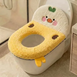 Close-up of a plush yellow duck toilet seat cover, embroidered face, green heart and dangling feet