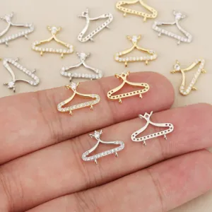 Gros plan sur des connecteurs miniatures en cintre, dorés ou argentés, avec zircons et petites boucles