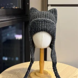 Close-up of the dark gray rib-knit texture, cat-ear crown and long braided ties on a winter hat