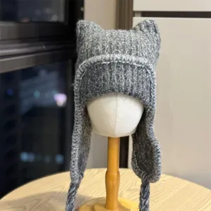 Close-up of chunky gray knit texture, pointed cat ears, long ear flaps and braided ties on display