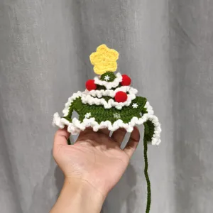 Hand-crocheted Christmas tree pet hat in green yarn, with a yellow star, red pom-poms and white trim