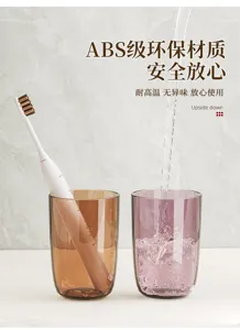Amber and purple translucent cups on marble; toothbrush in one, water pouring into the other