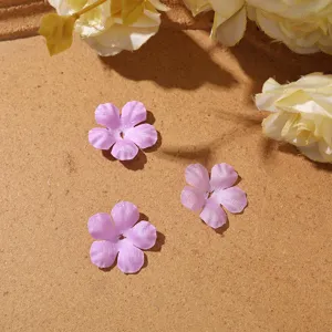 Three lilac satin flowers with six petals and center holes on a tan paper surface