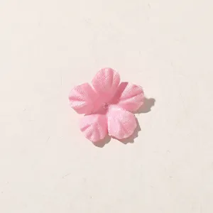 Close-up of a pink five-petal fabric flower with textured folds, centered on a pale background