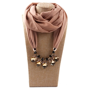 Detail of pink chiffon scarf with chunky amber gemstone necklace and gold accents