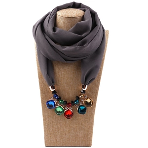 Detail of grey chiffon scarf necklace featuring large colorful gemstone embellishments