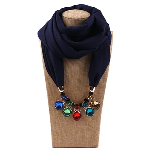 Detail of dark blue chiffon scarf featuring multi-colored gemstone pendants on mannequin