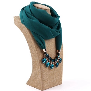 Detail of emerald green chiffon scarf necklace with ornate jewel pendant on a bust