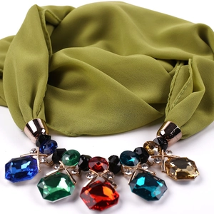 Macro shot of olive chiffon scarf necklace with large colorful faceted gemstones details
