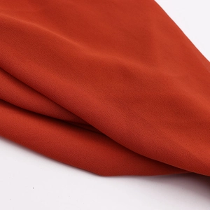Macro shot of breathable brick red pearl chiffon fabric texture with granular detail