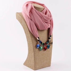 Detail of pink chiffon scarf necklace with multi-color gemstones on jewelry display stand