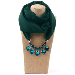 Detail of dark green chiffon scarf necklace with emerald gemstones and gold metal accents