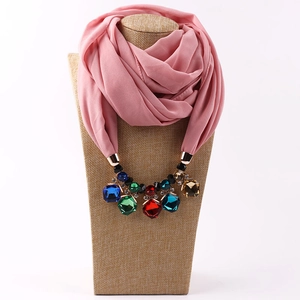 Detail of pink chiffon scarf necklace featuring multi-colored gemstone pendant on mannequin