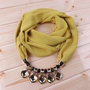 Detail of ginger yellow chiffon scarf with grey gemstone and gold alloy statement necklace