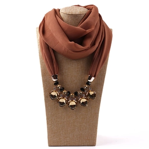 Detail view of caramel chiffon scarf necklace with amber crystal pendants on display stand