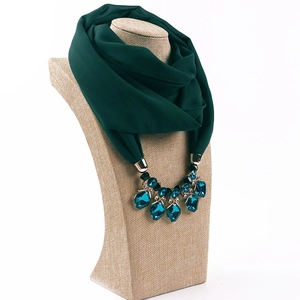 Detail of dark green chiffon scarf necklace with emerald synthetic gems on gold base