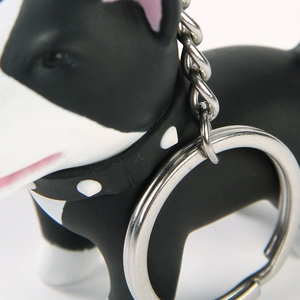 Detail of silver metal key ring and chain attached to a black and white dog pendant