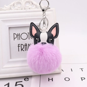 Close-up of a cute black and white dog keychain with a large purple fluffy faux fur pompom