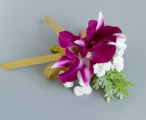 Detalle de un prendido de orquídea artificial púrpura con cinta dorada para bodas