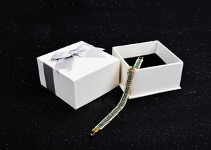 Gold-plated bracelet with blue and clear crystals in a white gift box with a grey bow