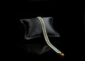 Macro view of gold-plated bracelet with blue and white crystals on black display