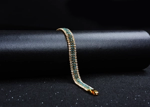 Detail of gold multi-layer bracelet featuring blue and clear rhinestones on a display