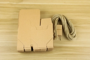 Flat lay of 10cm kraft paper gift boxes with natural jute twine and small tags for assembly
