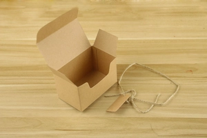Close-up of rectangular kraft paper favor box with natural twine and gift tag on wood
