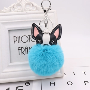 Detail of cute black and white PU leather puppy head with fluffy blue pom pom keychain