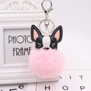 Detail of cute black and white puppy keychain with large pink plush pom-pom and metal clasp