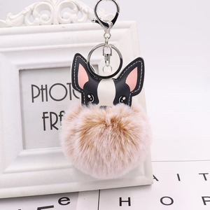 Close-up of a plush puppy keychain with a brown fur ball and silver metal hardware