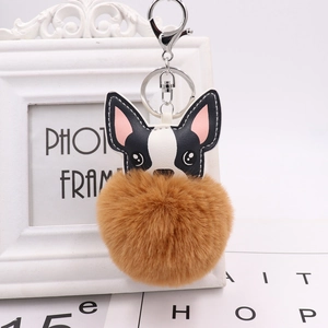 Detail of cute dog pompom keychain with PU leather dog head and brown fur ball