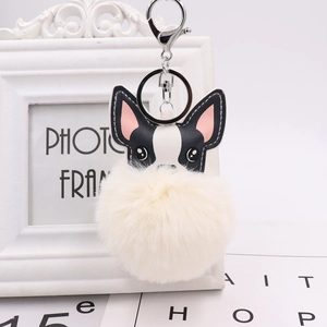 Detail of cute puppy plush ball keychain with faux leather and soft white fur pompom