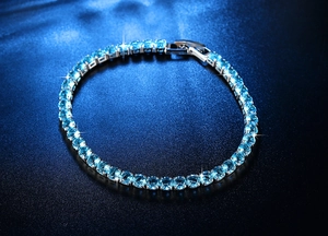 Nahaufnahme hellblauer Zirkonia-Steine in silberner Krappenfassung auf dem Armband