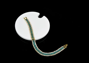 Detail view of a gold-plated bracelet with rows of blue and white sparkling rhinestones