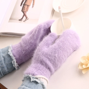 Close-up of soft light purple knitted plush gloves holding a white tea cup in winter