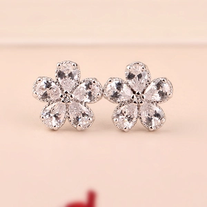 Close-up of silver flower stud earrings featuring five pear-cut clear gemstones