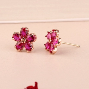 Detail of rose gold flower earrings with ruby pink gemstones in a five-petal floral design