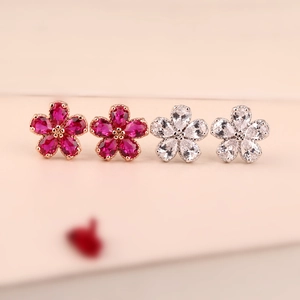 Macro detail of floral stud earrings with red and white corundum stones in claw setting