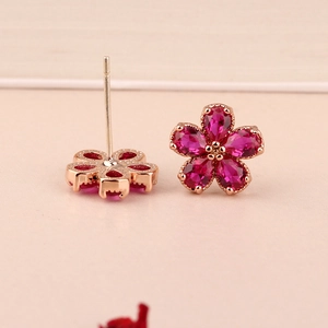 Macro shot of rose gold flower earrings with ruby rhinestones and 925 silver needles