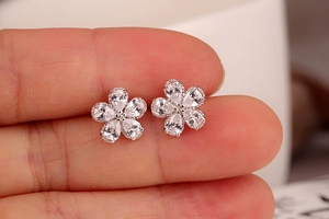 Macro close-up of a floral silver stud earring held by hand to show size and scale