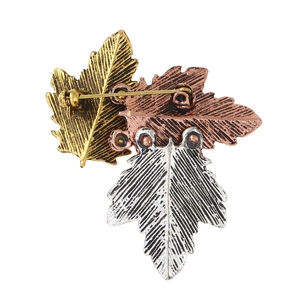 Detail view of the metal leaf brooch back showing textures in gold, rose gold and silver