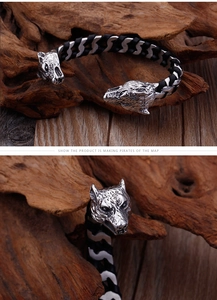 Detailed close-up of a double wolf head titanium steel bracelet with black leather cord